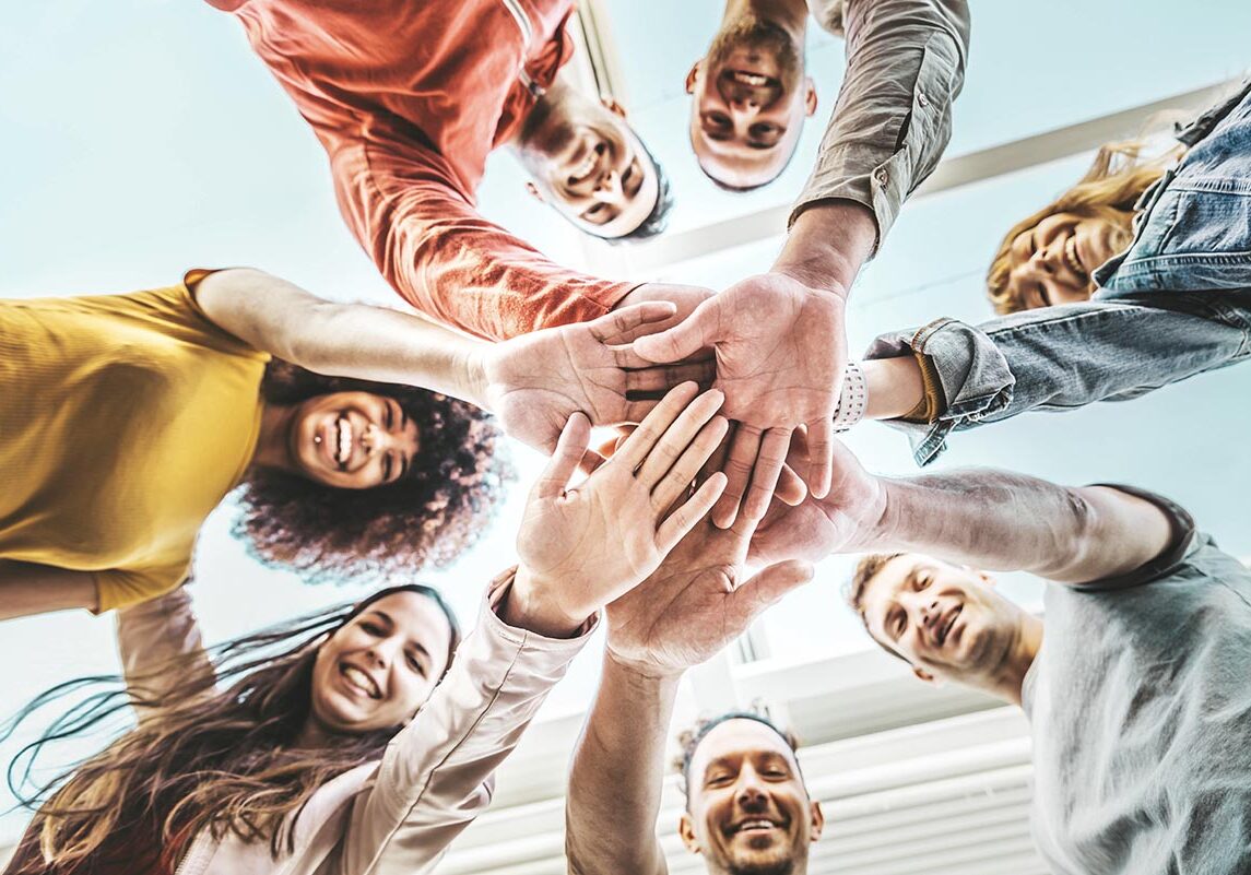 Group of young people stacking hands together outdoor - Community of multiracial international people supporting each other - Union, support and human resources concept