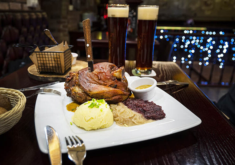 Czech dish - Veprevo knee in a dish with gravy pork knee with potatoes and honey mustard. A large portion of grilled pork and beer on the table in the pub.